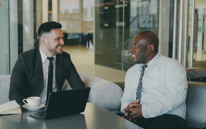 Two professionally dressed men talking at work.
