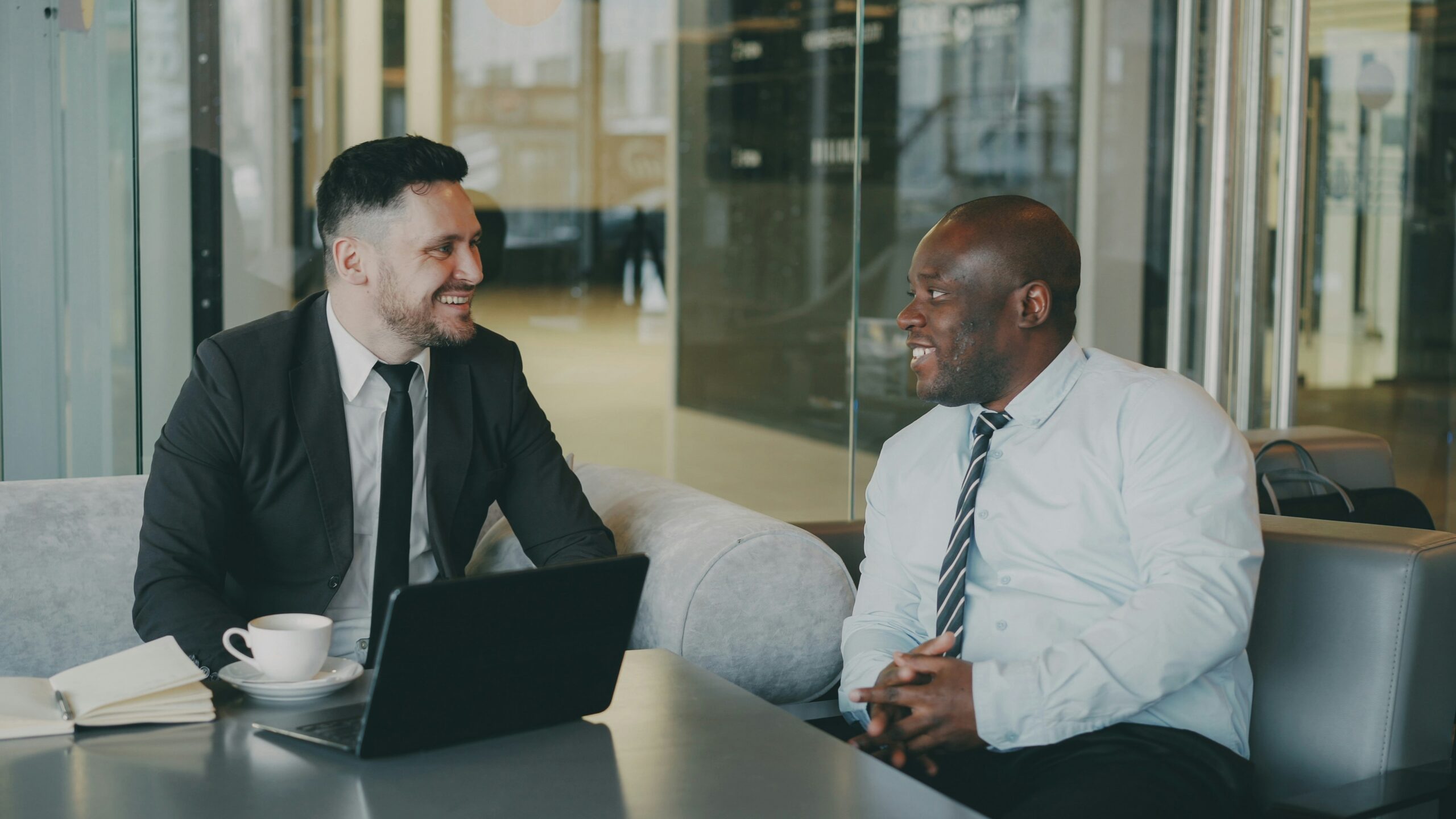 Two professionally dressed men talking at work.